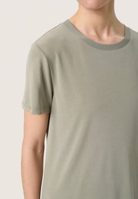 T-shirt verde chiaro realizzato in tessuto morbido, con colletto rotondo e maniche corte, arricchito da dettagli di cucitura delicati.