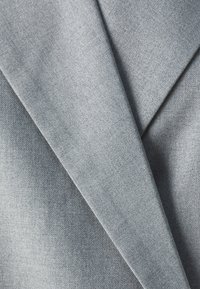 Grått stoff med diagonale folder som viser en jevn tekstur og fin veving. Materialet har en dempet, enhetlig farge med myk glans.