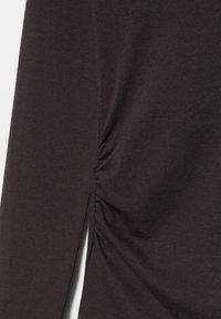 Braunes langärmliges Oberteil aus weichem Stoff, mit gerafften Seitendetails und einem kleinen Schlitz am Saum für eine lässige Passform.