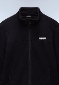 Black fleece jacket with a high collar, front zip, and two side pockets. Features a logo patch on the chest and a smooth texture.