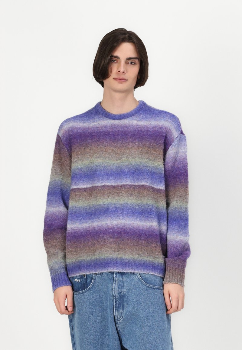 Paars en bruine gestreepte trui, gemaakt van een zachte brei stof, met een ronde hals en geribde boorden. Casual pasvorm, gedragen met denim.