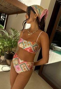Dviejų dalių bikini rinkinys ryškiomis pastelinėmis spalvomis su raštuotu trumpu viršutiniu ir aukšto juosmens apatinių dalių su dekoratyviniais kriauklių motyvais.