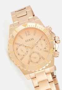 Orologio cronografo Guess in tono dorato con quadrante circolare, tre sottodial e bracciale a maglie in metallo. Presenta ampi indici di ore in grassetto.
