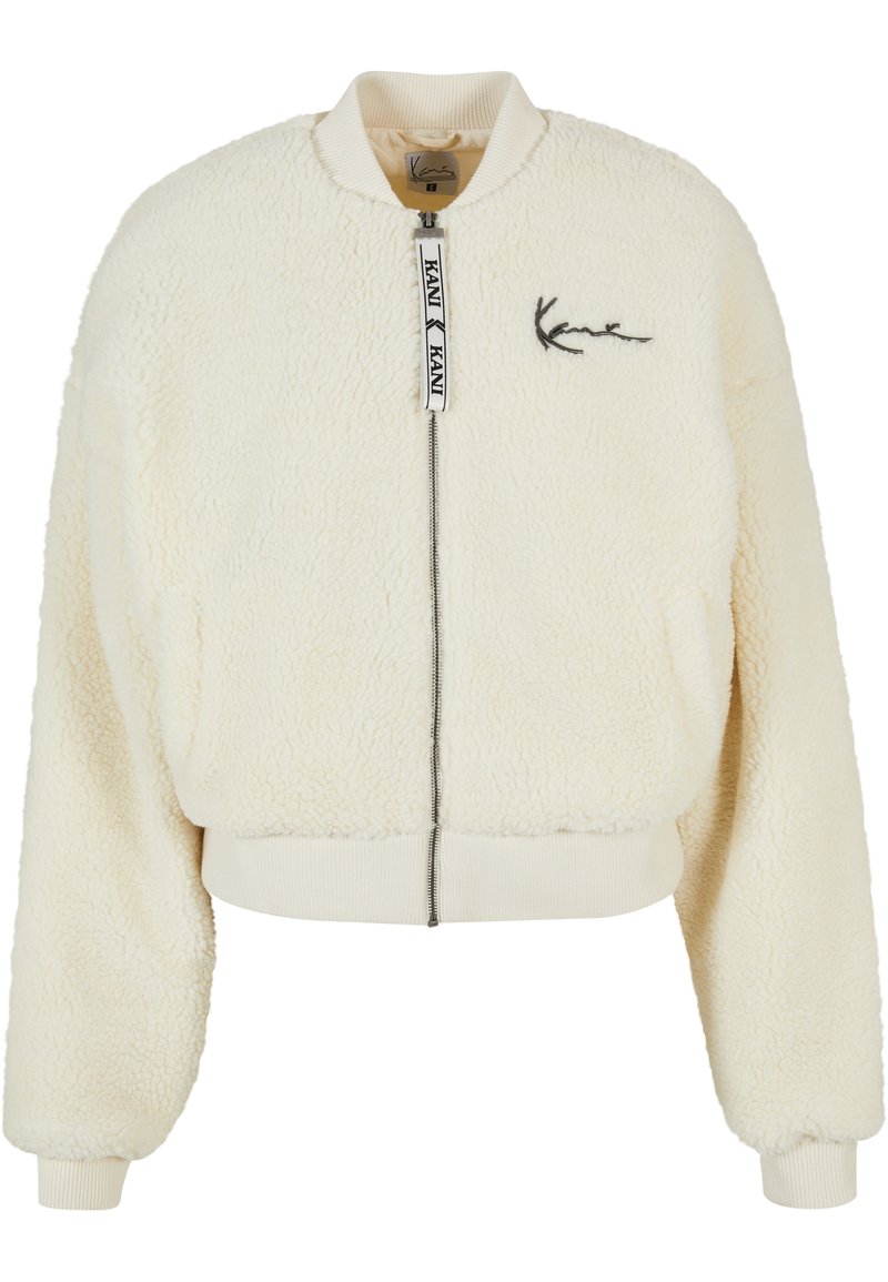 Giacca bomber color crema realizzata in materiale di pelliccia sintetica testurizzata, con polsini a coste e chiusura con zip. Presenta un ricamo del logo discreto sul petto.
