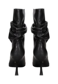 Stivali neri in pelle con gambale morbido e drappeggiato, tacco a spillo e texture liscia. La vista posteriore evidenzia il tacco arrotondato e i dettagli delle cuciture.