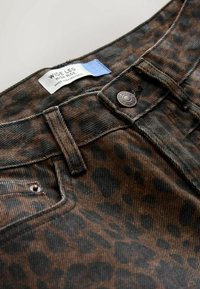 Breda ben, hög midja jeans i ett brunt och svart leopardmönster. Funktioner fyra fickor, metallknappsstängning och ett tygmärke.