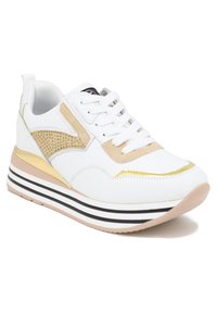 Sneaker atletica bianca con dettagli in camoscio beige, accessori in oro e inserti in rete. Presenta una suola a strati con strisce nere e bianche.
