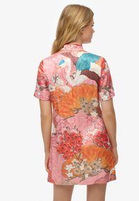 Vestido de seda rosa con estampado colorido de flores y grúas, mangas cortas y cuello mandarín con cierre trasero. Textura suave.