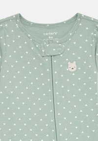 Light green romper with white heart patterns, featuring a front snap closure, short sleeves, and a small bear embroidery accent.