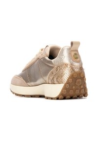 La zapatilla presenta un upper metálico dorado y beige, acentos de gamuza, un talón texturizado y una suela blanca gruesa con una banda de rodadura de goma con patrón.