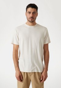 Kurzarm-T-Shirt mit Rundhalsausschnitt in Off-White mit senkrellem Rippstruktur. Weicher Stoff, taillierte Passform und saubere Verarbeitungsdetails.