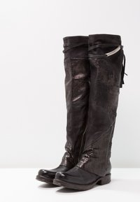 Knee-high black boots with a mix of matte and textured finishes, featuring side zip closure, decorative ties, and a low chunky heel.