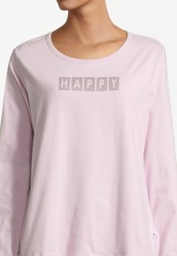 Light pink long-sleeve shirt featuring the word "HAPPY" in block letters with a striped texture across the chest area. Soft cotton material.