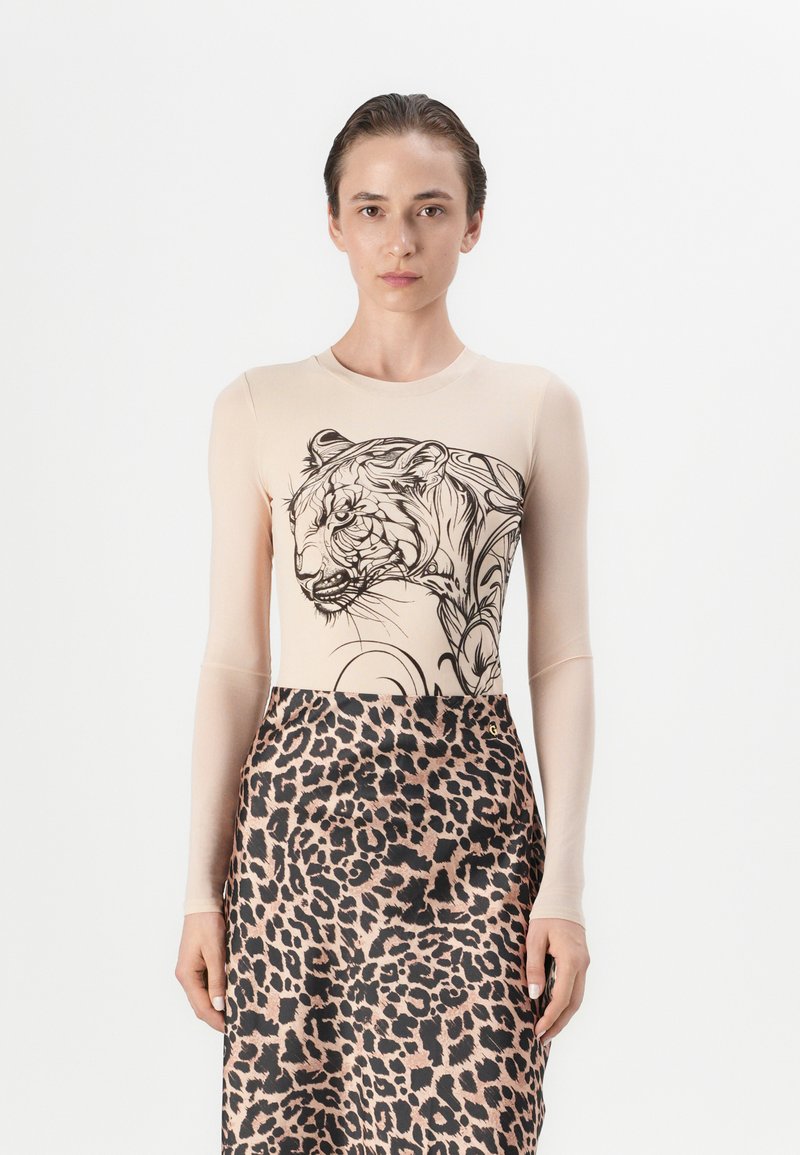 Langsleeve bodysuit in beige met zwarte tijgerafbeelding, gecombineerd met een midi-lengte rok met een luipaardprint. Soepele textuur.