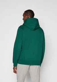 Groene hoodie met een casual pasvorm en ribgebreide manchetten, gemaakt van zachte stof. Zichtbare capuchon en buidelzak aan de voorkant.