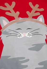 Gato gris con diadema de astas sobre un fondo rojo; presenta ojos cerrados, bigotes y una textura suave en el diseño.