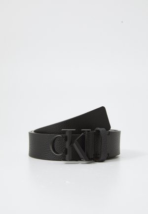 Ceinture en cuir noir avec une finition texturée, dotée d'une boucle en métal noir mat portant le logo "ck", conçue pour un look épuré.