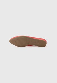 Semelle d'une chaussure plate rouge à bout pointu avec une semelle antidérapante marron texturée, taille 42, présentée sur un fond blanc uni.