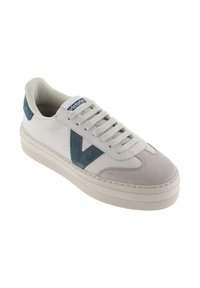 Vit sneaker med mockadetaljer i ljusgrått och teal, har platta snören, rund tå och en texturerad gummisula. Logotyp på tungan.