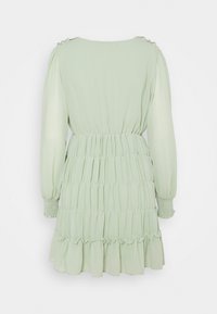 Limettengrünes Kleid mit langen Ärmeln, gerafftem Taillenbund und gestuftem Rüschensaum. Glattes Stoff mit subtiler Struktur und gerafften Schulterdetails.