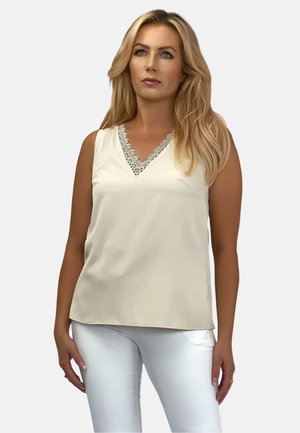 Sleeveless beige blouse with a V-neck, featuring white lace detailing along the neckline. Smooth fabric with a loose fit.