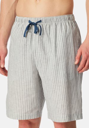 Jasnoszare spodenki z białymi pionowymi paskami i granatowym sznurkiem, noszone przez stojący męski tors, pokazujące ręce i długość do połowy uda.