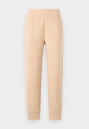 Beige-housut pehmeästä kankaasta, joissa on ribattu vyötärö, kapenevat hihnat ja värisävyyn sointuva sivukuosi, jossa on geometrinen muotoilu.