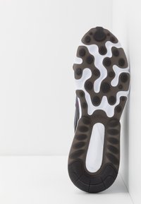Podešev boty s výrazným designem s černými gumovými akcenty a kruhovými bílými vložkami, texturovaná pro lepší přilnavost, se středovým výřezem.