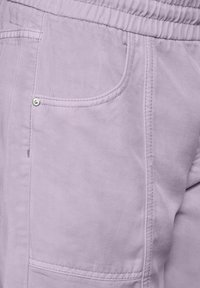 Pantalons cargo en tissu lavande clair avec une finition texturée, comportant des poches avant et une taille élastique pour un confort optimal.