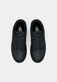Nike tenisice u tamnozelenoj boji s glatkom, teksturiranom završnom obradom; s perforiranim prednjim dijelom, tamnim vezicama i potpisanim logotipom na jeziku.