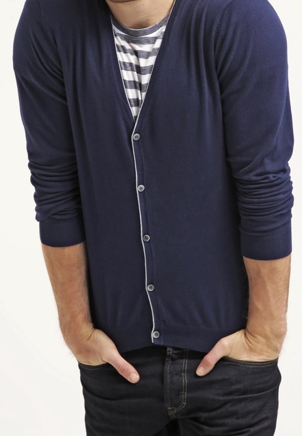 Marinblå cardigan tillverkad av mjukt material, med V-ringning, lång ärm och en kontrasterande randig skjorta under, knäppt med knappar.