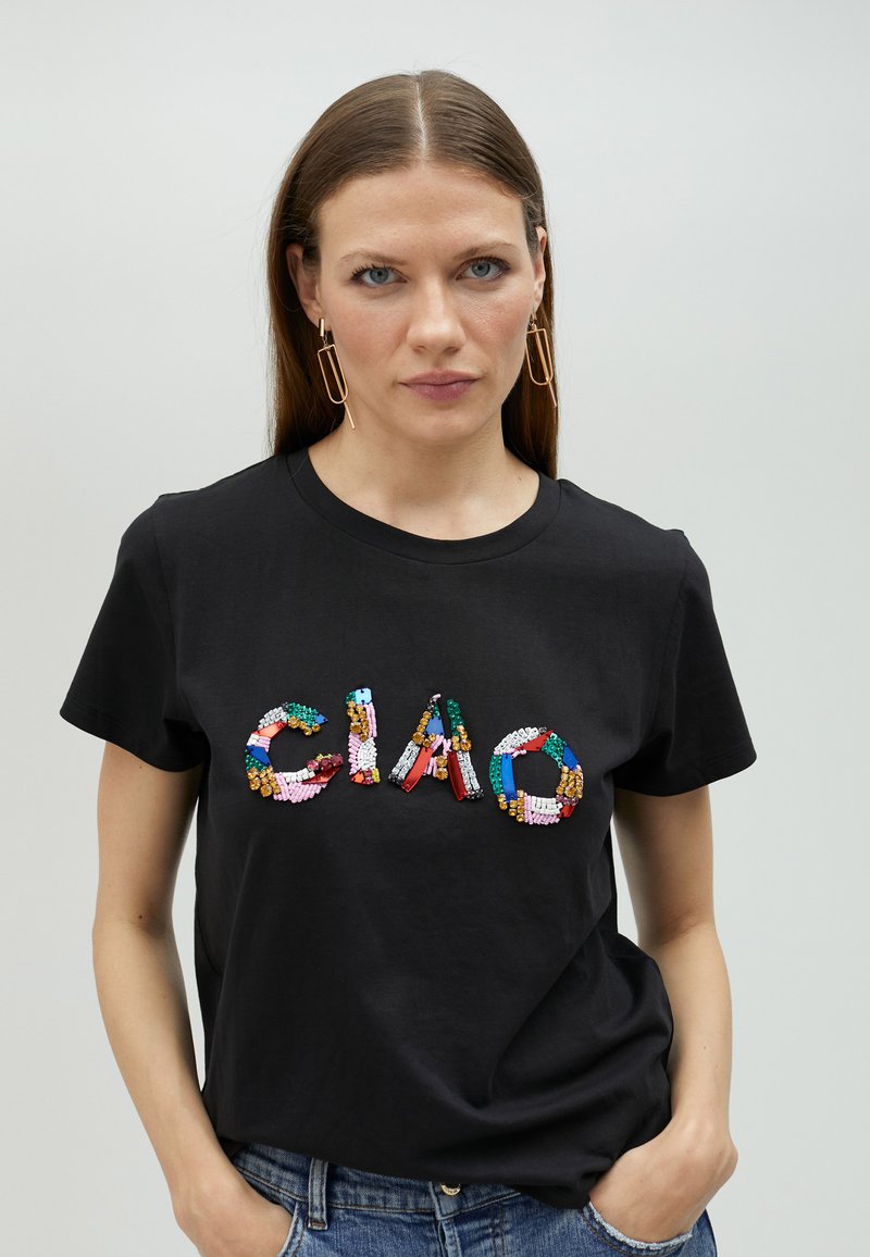 Svart bomullströja med ordet "Ciao" i färgglada, texturerade pärlor. Ljusare passform med korta ärmar och rund halsringning.