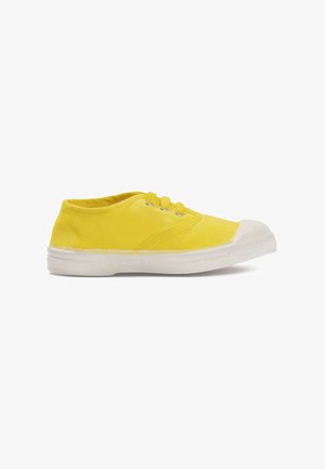 Baskets basses en toile jaune avec une semelle et un embout en caoutchouc blanc, dotées de trois œillets jaunes et de lacets, sur fond blanc.