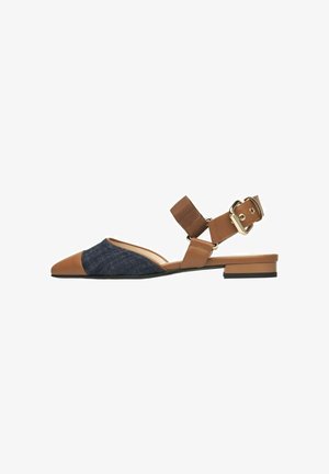 Brown and navy two-tone flat sandal with a pointed toe, a denim upper, and a brown ankle strap featuring a gold buckle detail.