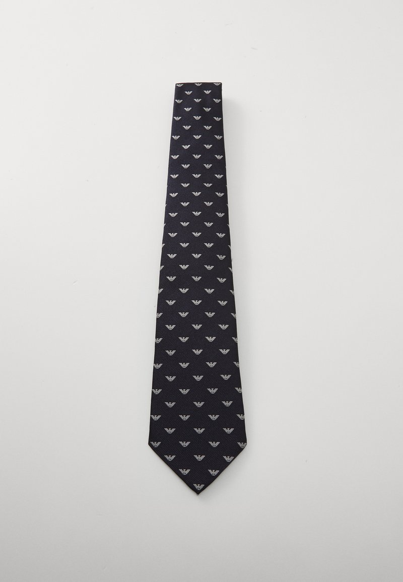 Merimustavihik, millel on korduv helehall lehemuster, valmistatud tekstureeritud kanga, terava otsaga ja kitsas kujuga.