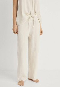 Ljust beige, texturerade loungebyxor med en lös passform och resårmed bälte, parat med en matchande ärmlös topp. Mjuk, andningsbar tyg.