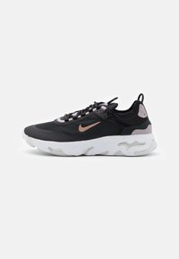 Čierne a šedé tenisky s priedušným zvrškom, bielou gumovou podrážkou a svetloružovými akcentmi. Výrazné logo Nike na boku.