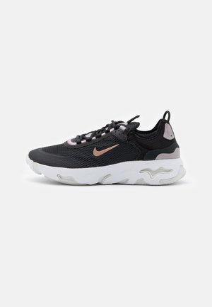 Fekete és szürke sneaker, mesh felsőrésszel, fehér gumi talppal és világos rózsaszín részletekkel. Jellegzetes Nike logó az oldalon.