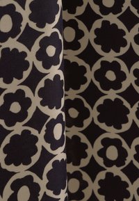 Tkanina z granatowym wzorem kwiatowym na kremowym tle, z koncentrycznymi okręgami i skomplikowanymi kształtami kwiatów. Gładka tekstura, mieszanka bawełny.