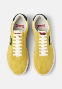 Yellow leather sneakers with a smooth finish, white laces, green accent on the side, and a white rubber sole. Red "CAMPER" branding inside.
