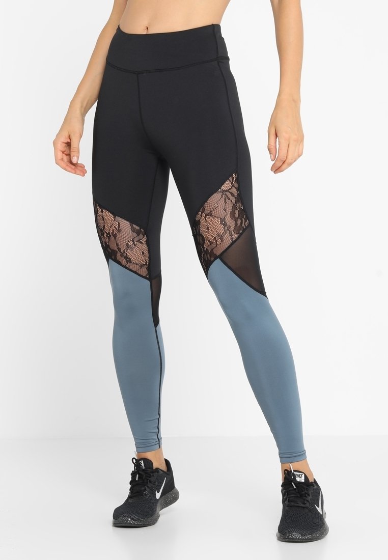 Leggings neri con pannelli in pizzo e rete, caratterizzati da una parte inferiore blu chiaro e una vita alta. Realizzati in materiale elasticizzato e traspirante.