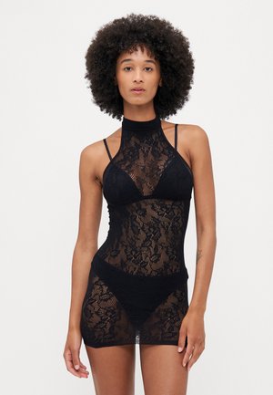 Rochie din dantelă neagră cu guler înalt, având modele florale complicate, bretele subțiri și un design ajustat, evidențiind un material transparent.