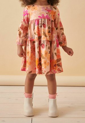 Robe fleurie aux tons roses et orange avec manches longues, taille froncée, jupe à volants et bottines blanches avec chaussettes roses.