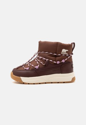 Bottine marron imperméable et isolée avec semelle blanche et lacets violets à motifs, avec le logo Sorel et une languette à l'arrière.