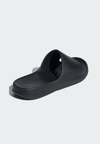 Black slide sandal made of flexible material with a textured footbed, featuring a raised design on the strap and a contoured sole for comfort.