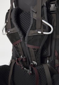 Zaino nero con imbottitura in rete regolabile e spallacci in webbing; presenta elementi metallici e scomparti con zip per riporre oggetti.