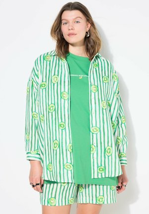 Grün-weiß gestreifte Bluse mit Kiwi-Muster, kombiniert mit einem einfarbigen grünen T-Shirt und passenden Shorts, die einen entspannten Schnitt und einen Knopfverschluss aufweisen.