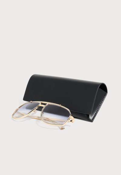 Lunettes de soleil à monture dorée avec verres teintés reposant devant un élégant étui en cuir noir sur une surface blanche.