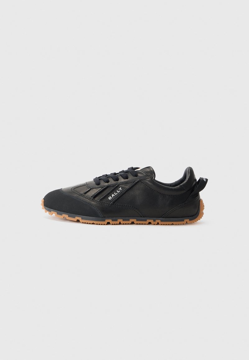 Scarpa sportiva nera con tomaia in pelle texturizzata, suola in gomma e lacci. Presenta un logo sul lato e un'etichetta sul tallone.