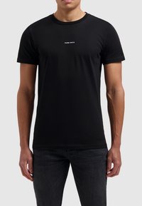Zwarte katoenen t-shirt met een ronde hals en korte mouwen. Voorzien van witte tekst "PURE PATH" op de voorkant, gladde textuur en slim fit.